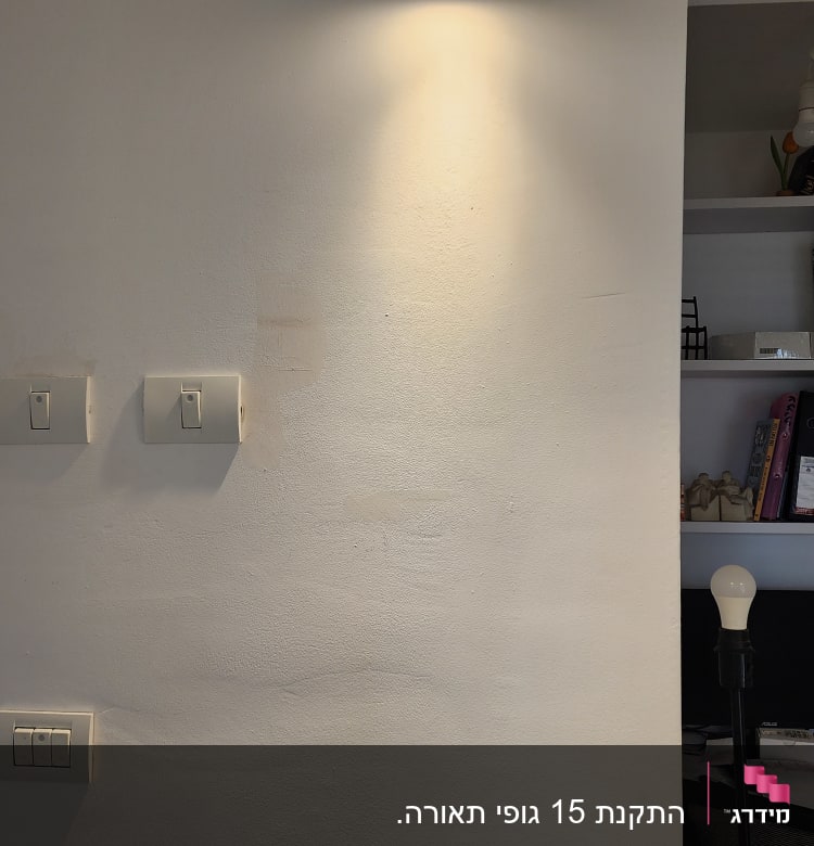 מנורת קיר דולקת ומתגי חשמל על הקיר